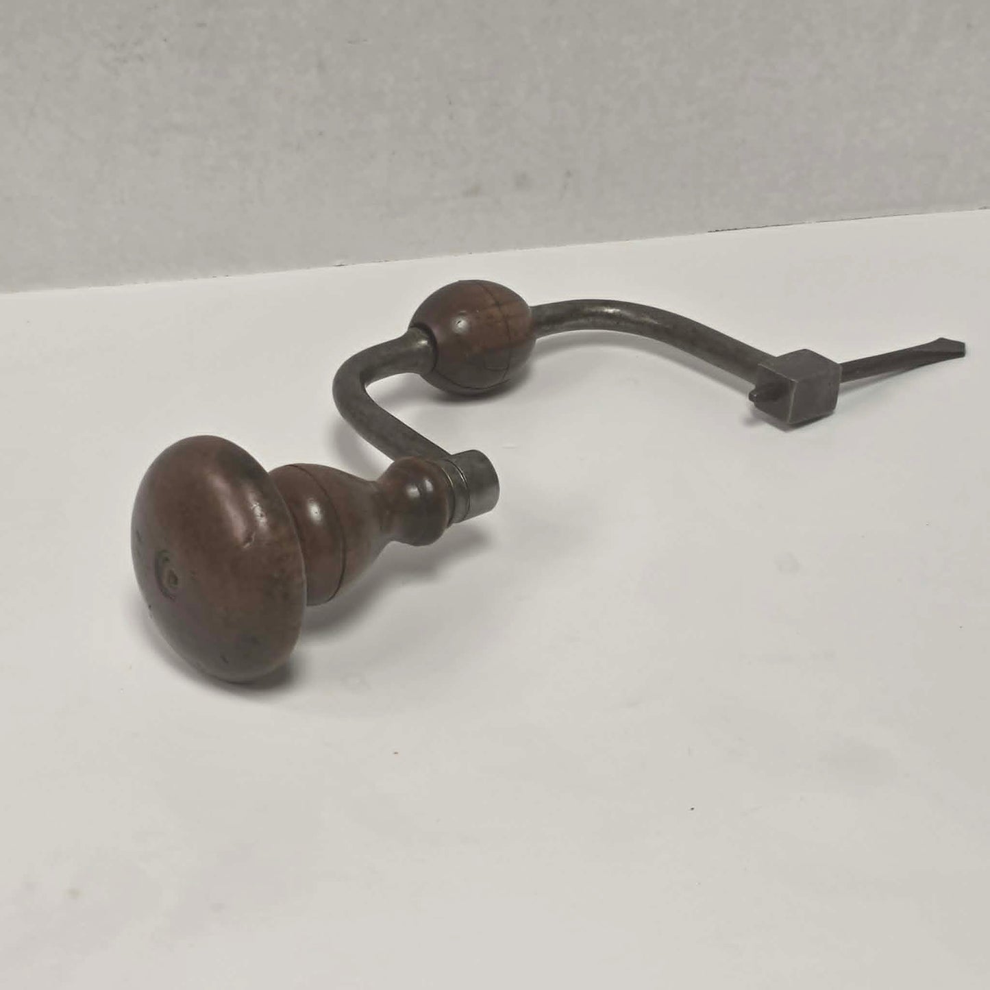 An exquisitely crafted antique walnut-handled bit brace that showcases the beauty and precision of early woodworking tools.
