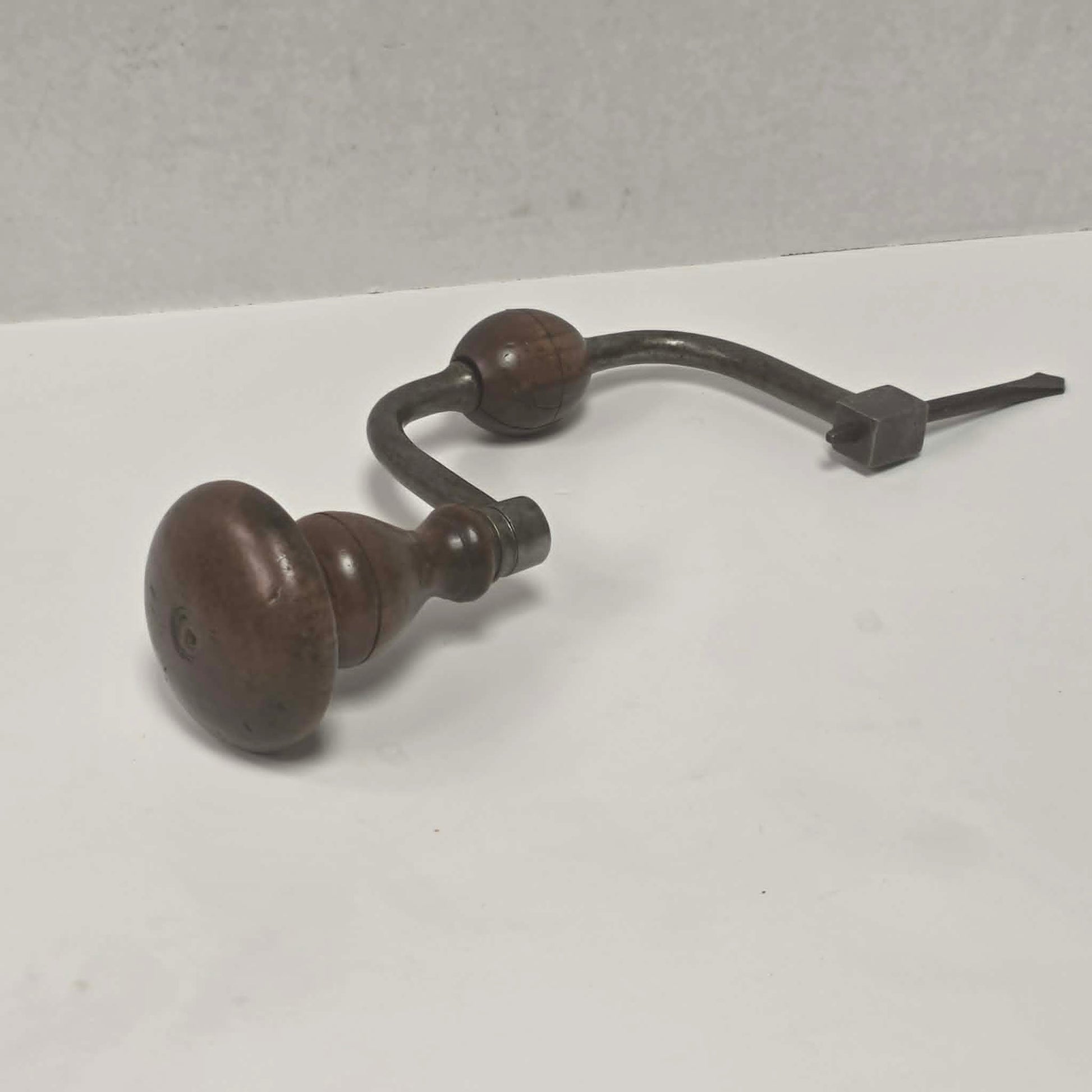 An exquisitely crafted antique walnut-handled bit brace that showcases the beauty and precision of early woodworking tools.
