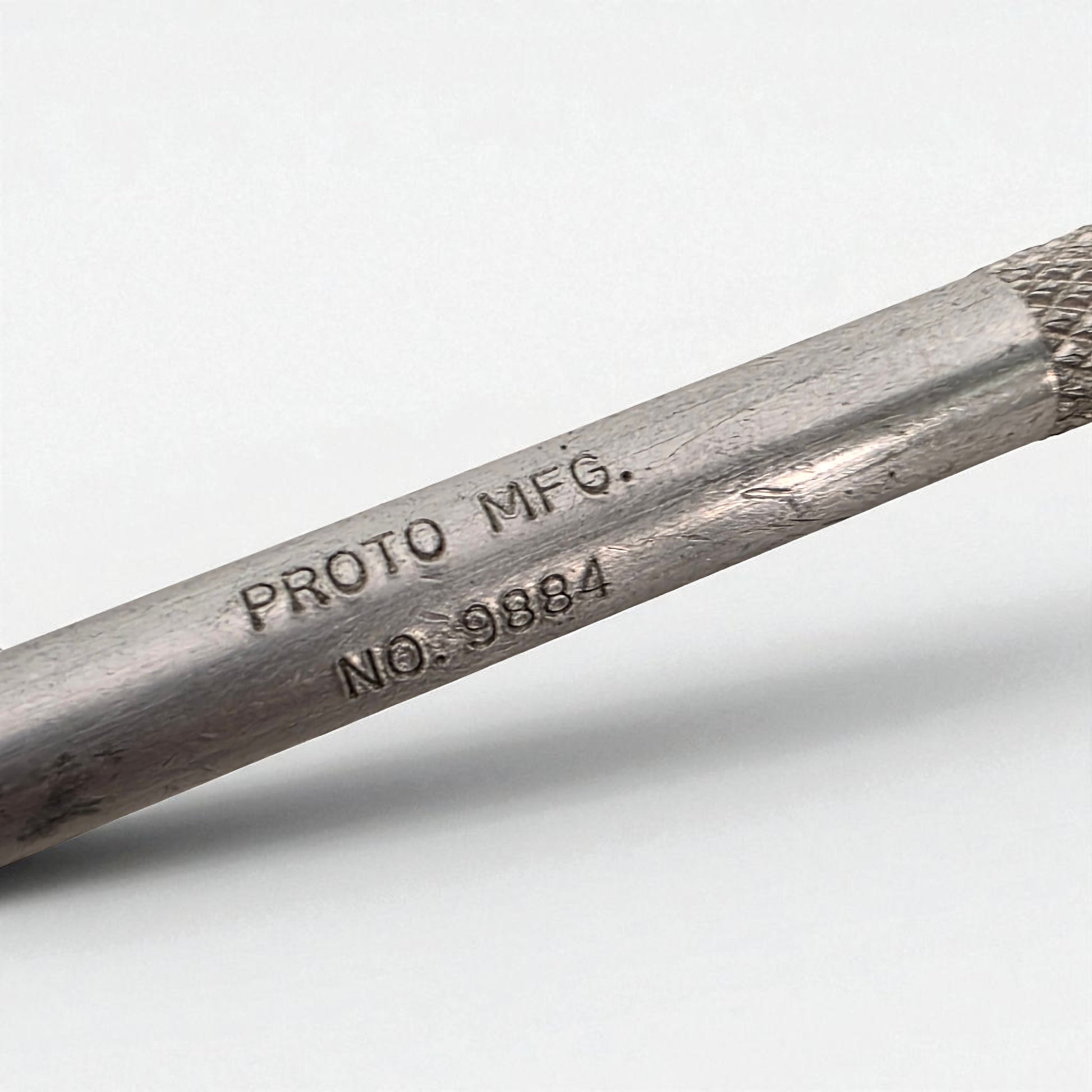 Metal rod with 'PROTO MFG.' and 'NO. 9884' engraving on a white background
