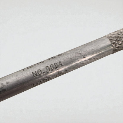 Close-up of a metal tool with engraved text on a light gray background