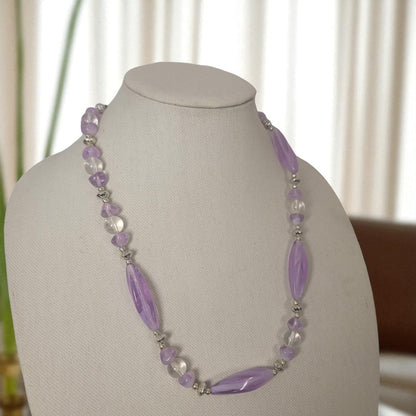 Necklace with purple beads on a mannequin bust against a neutral background