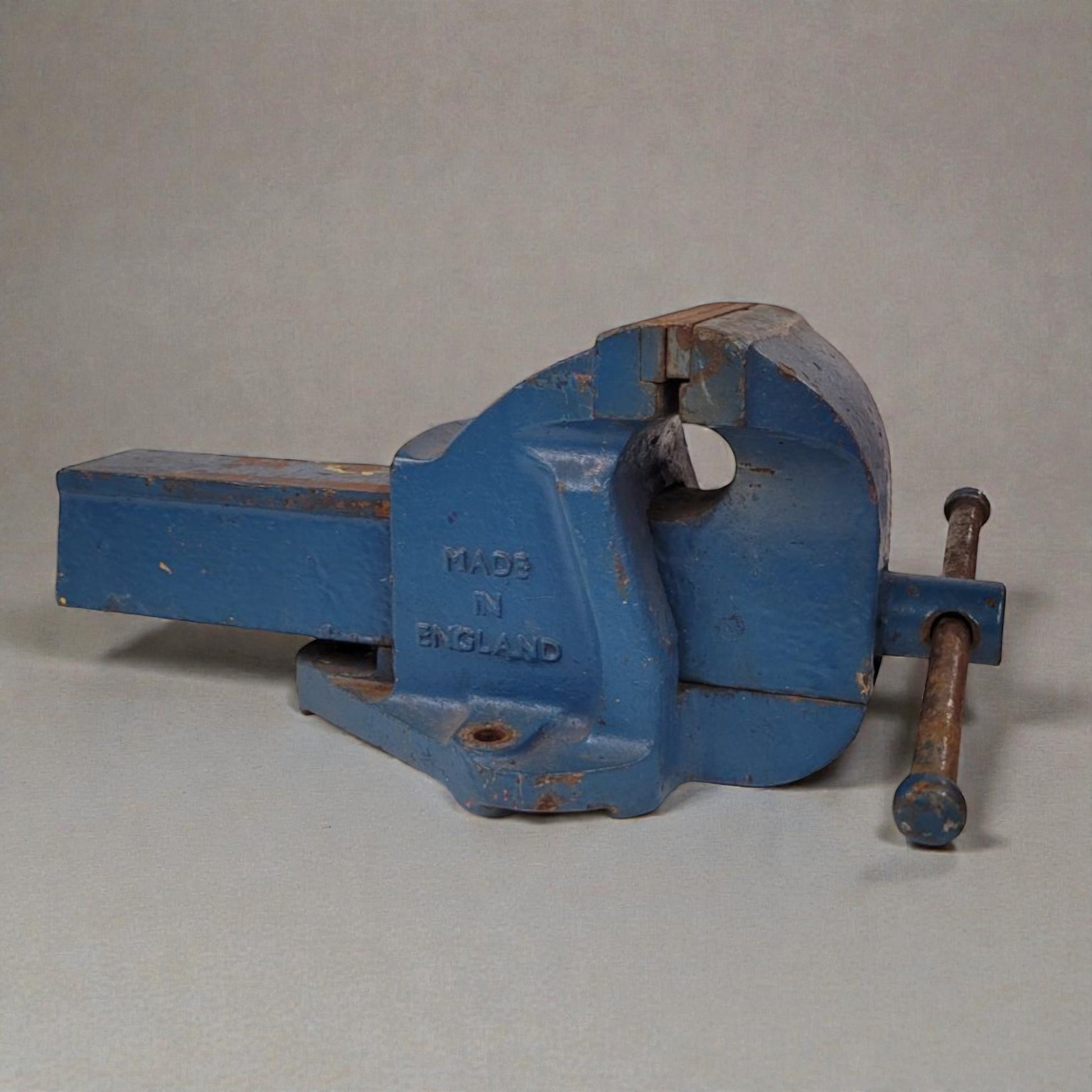 Blue metal vise with 'Made in England' inscription on a light gray background