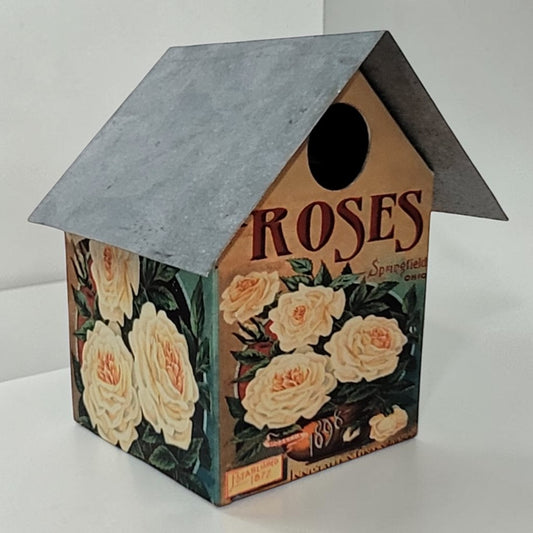 Handcrafted rustic rose-themed birdhouse made from reclaimed materials for garden and outdoor décor.
