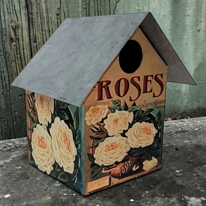 Handcrafted rustic rose-themed birdhouse made from reclaimed materials for garden and outdoor décor.
