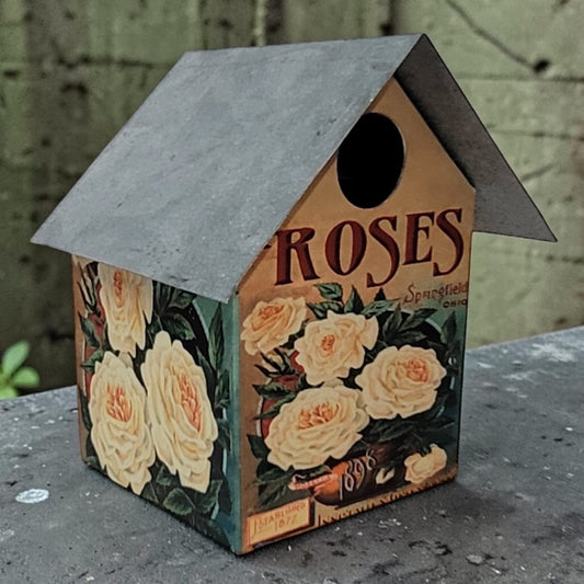 Handcrafted rustic rose-themed birdhouse made from reclaimed materials for garden and outdoor décor.
