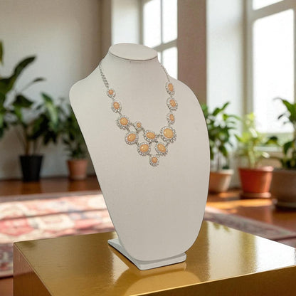Necklace on a white bust against a blurred indoor background with plants
