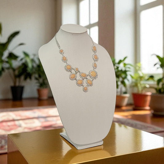 Necklace on a white bust against a blurred indoor background with plants