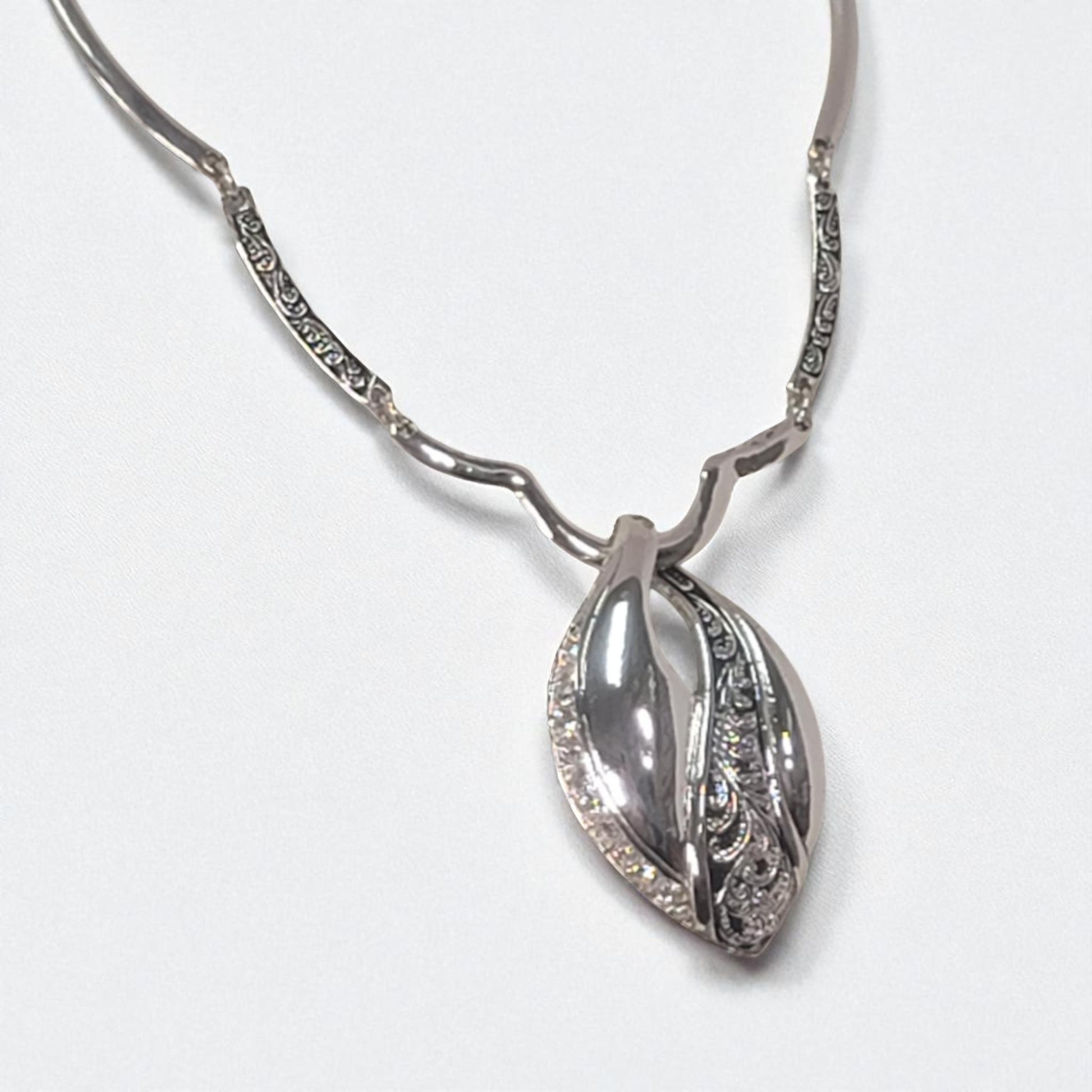 Silver necklace with a leaf-shaped pendant on a white background