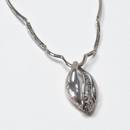 Silver necklace with a leaf-shaped pendant on a white background