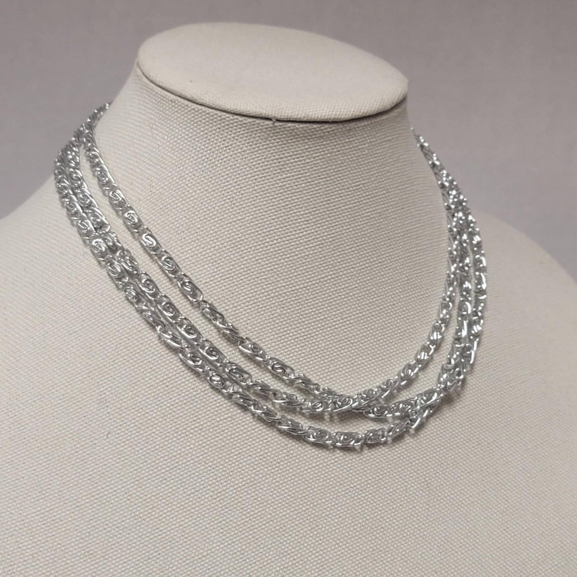 Silver chain necklace on a mannequin bust against a neutral background