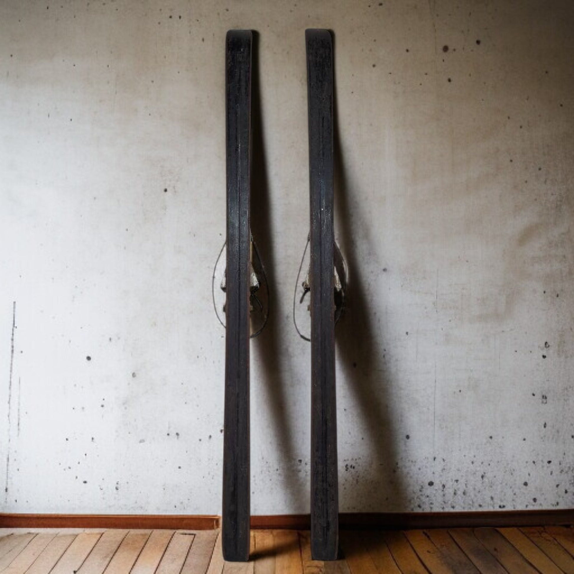 Two large black metal objects leaning against a textured wall.