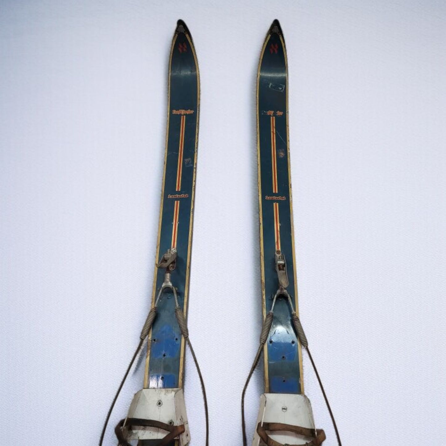 Pair of vintage skis with leather straps on a white background