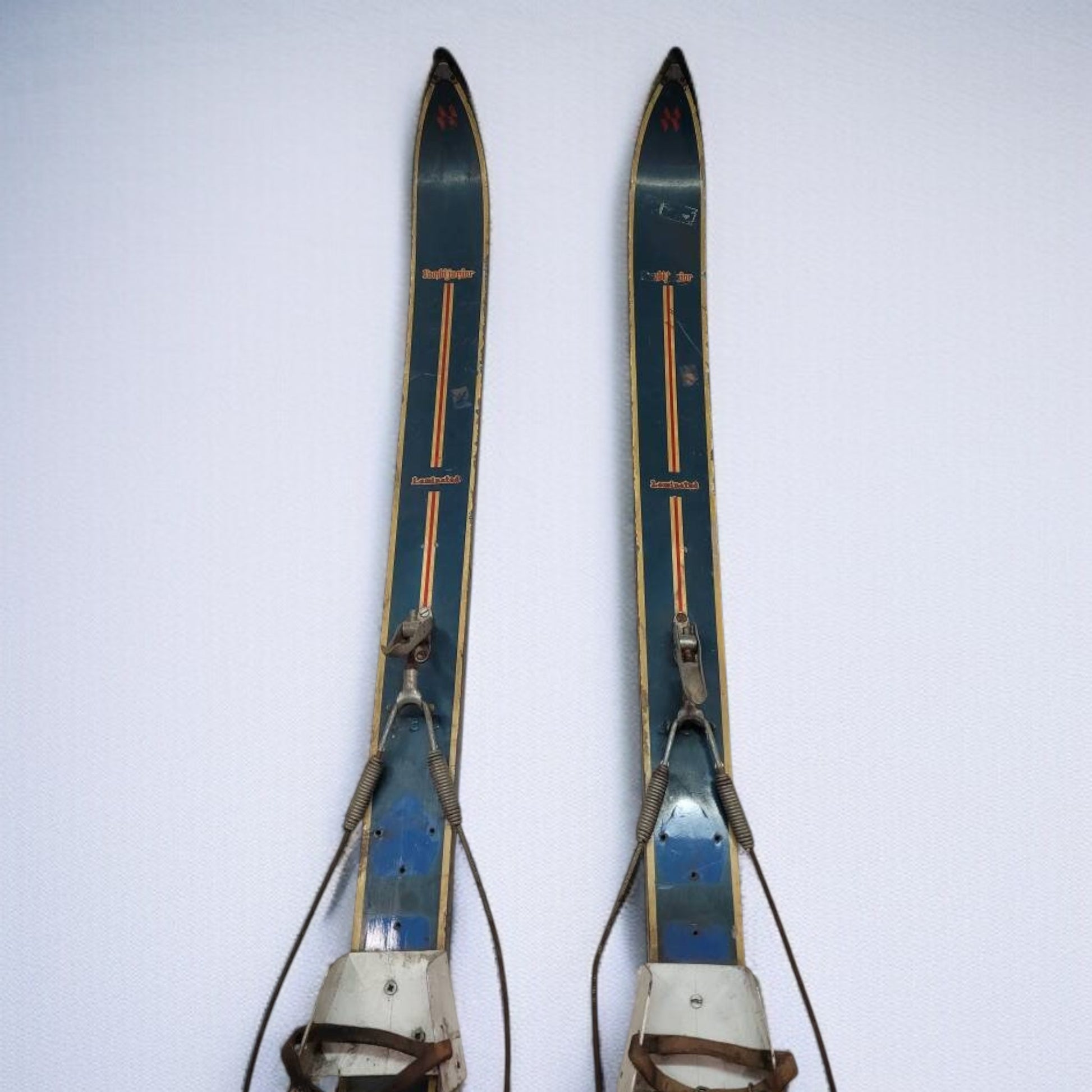 Pair of vintage skis with leather straps on a white background