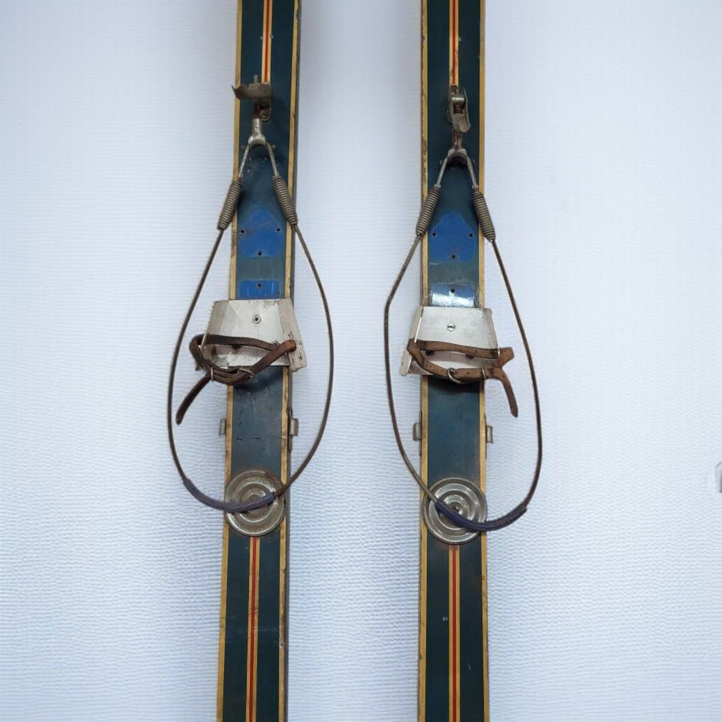 Pair of vintage skis with metal bindings on a light blue background
