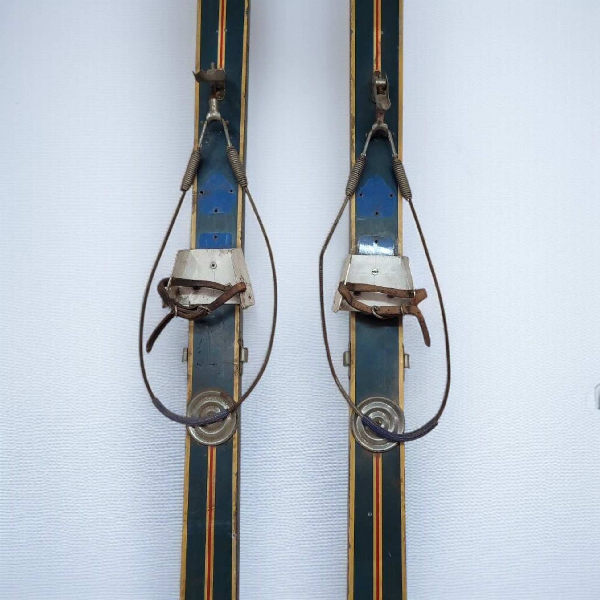 Pair of vintage skis with metal bindings on a light blue background