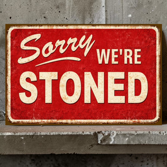 Red sign with 'Sorry We're Stoned' text on a concrete wall.