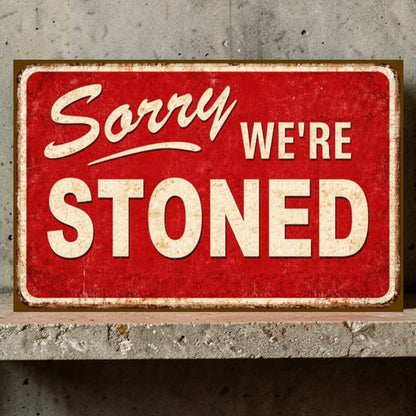 Red sign with 'Sorry WE'RE STONED' text on a concrete wall background