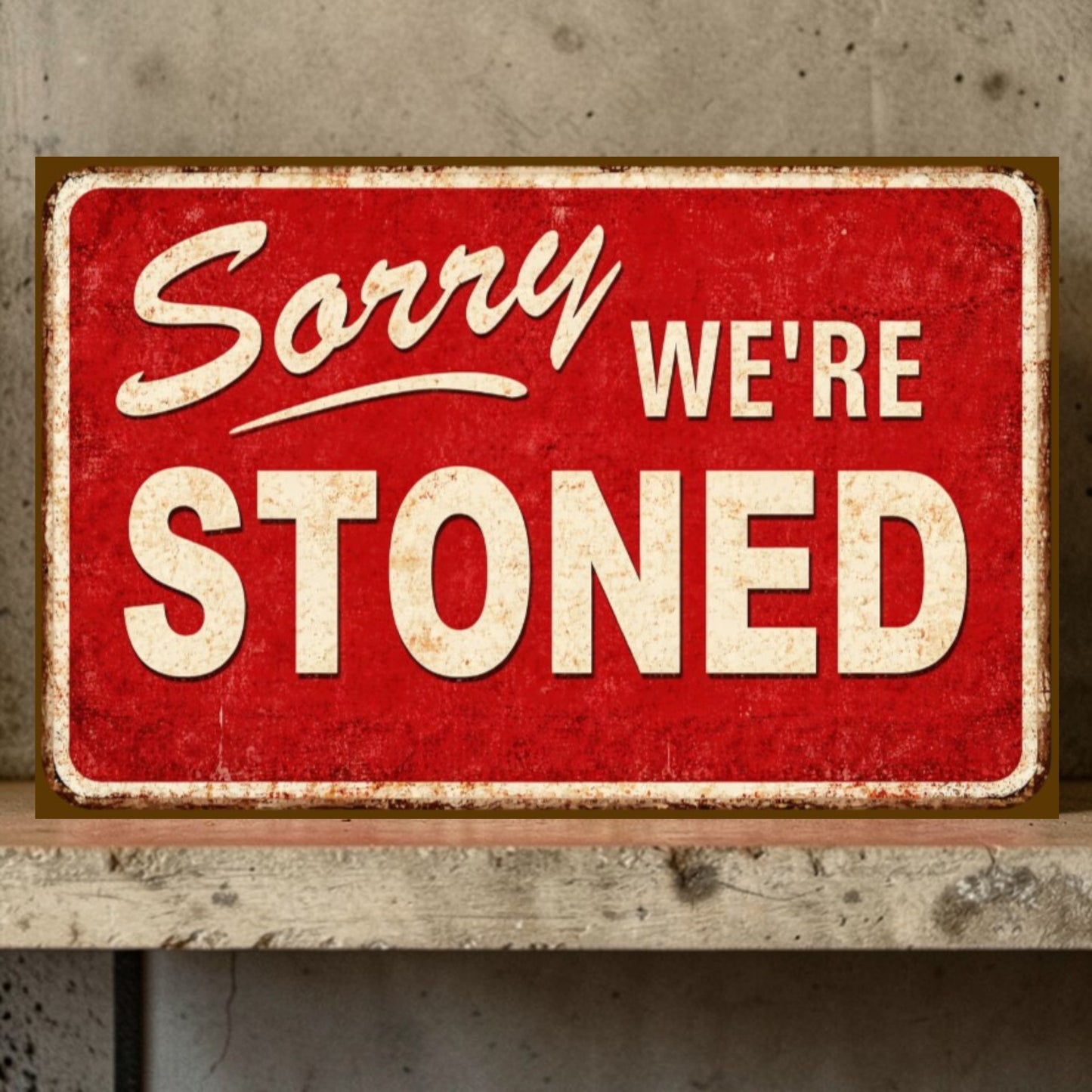 Red sign with white text 'Sorry WE'RE STONED' on a wooden surface.