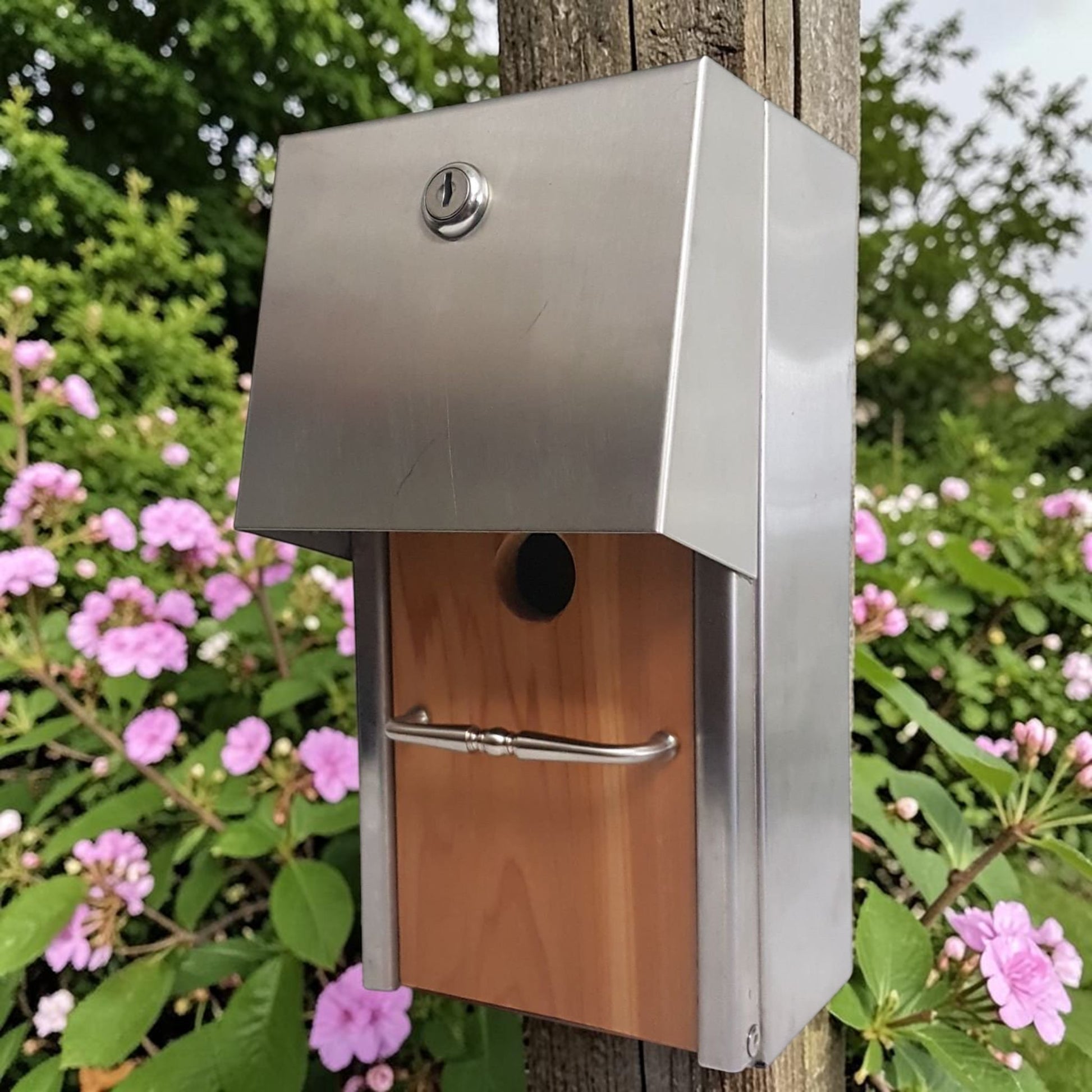 Handmade stainless steel birdhouse with sleek architectural styling and locking access door.