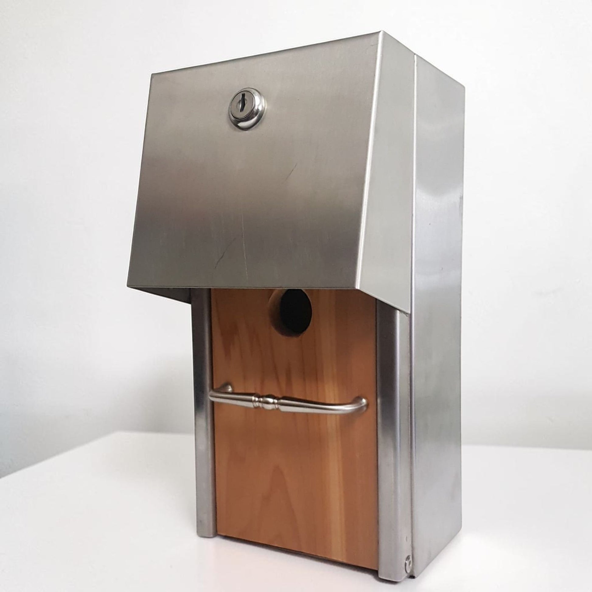 Handmade stainless steel birdhouse with sleek architectural styling and locking access door.