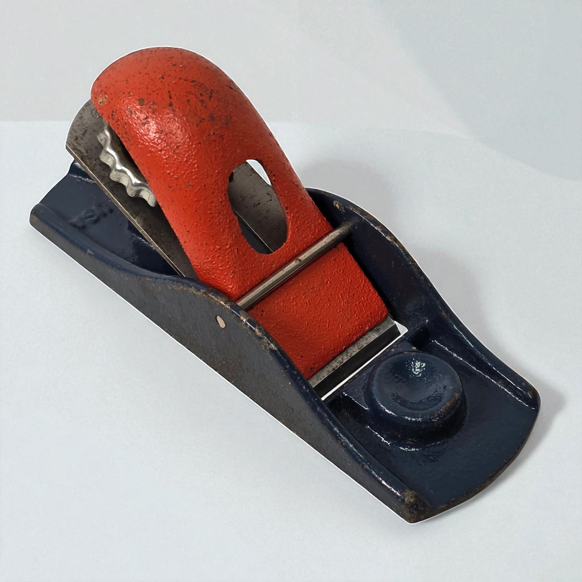 Vintage hand plane with red handle and black metal body on a white background