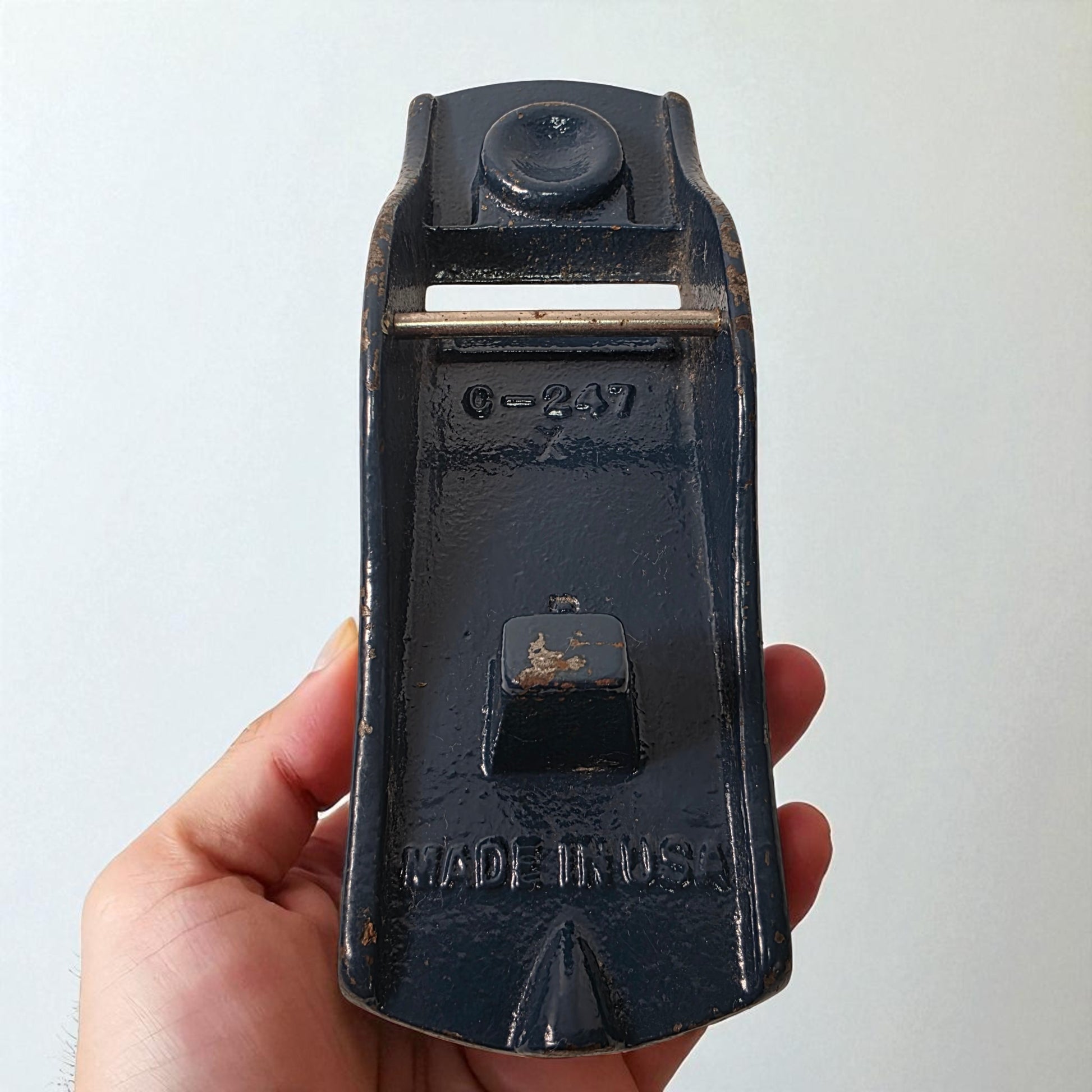 Vintage black tool with 'Made in USA' text held in a hand against a white background