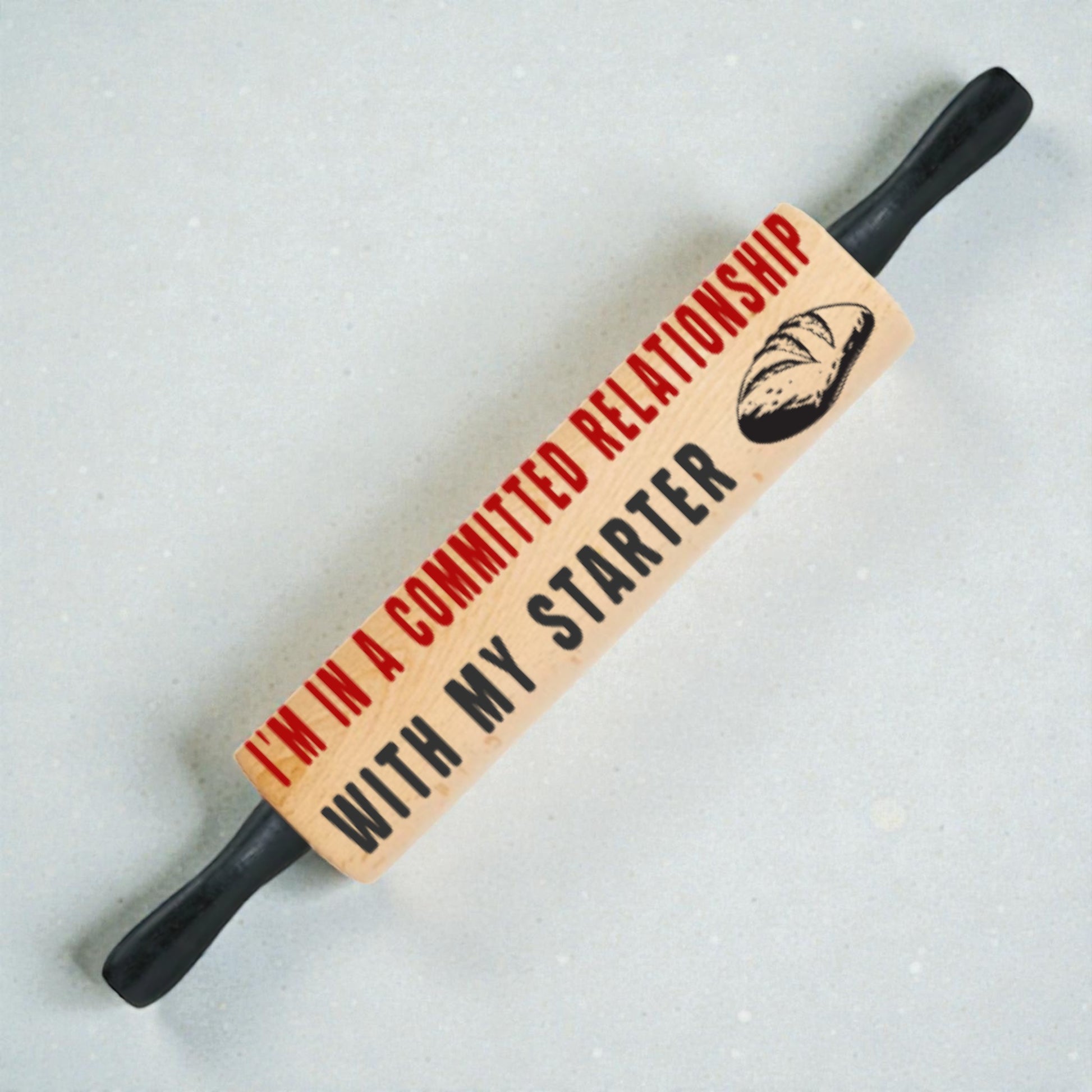 Rolling pin with humorous text and bread graphic on a light background