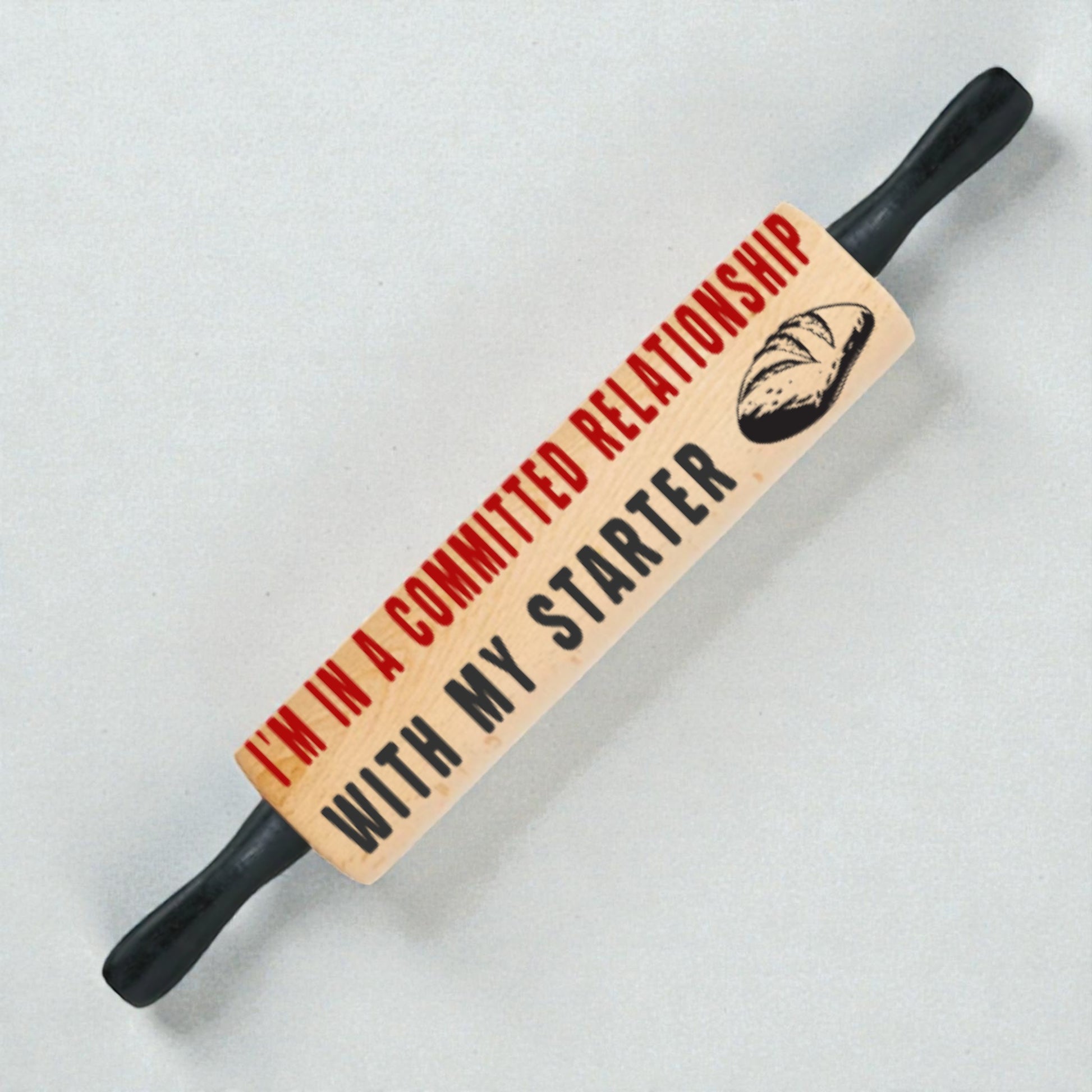 Rolling pin with humorous text and bread graphic on a light background