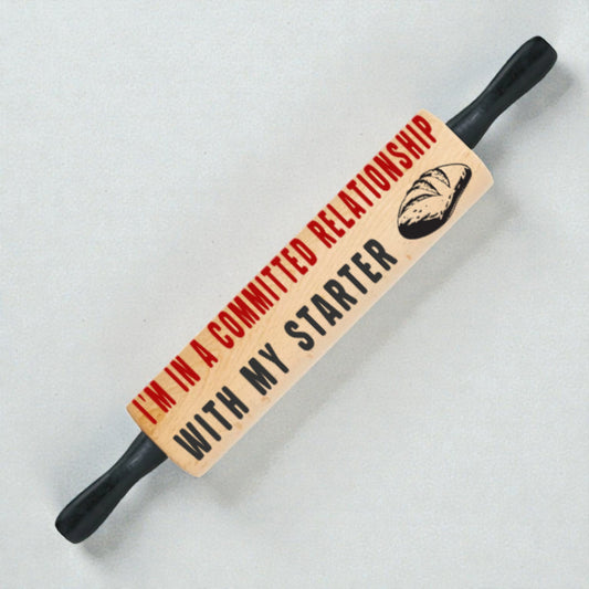 Rolling pin with humorous text and bread graphic on a light background