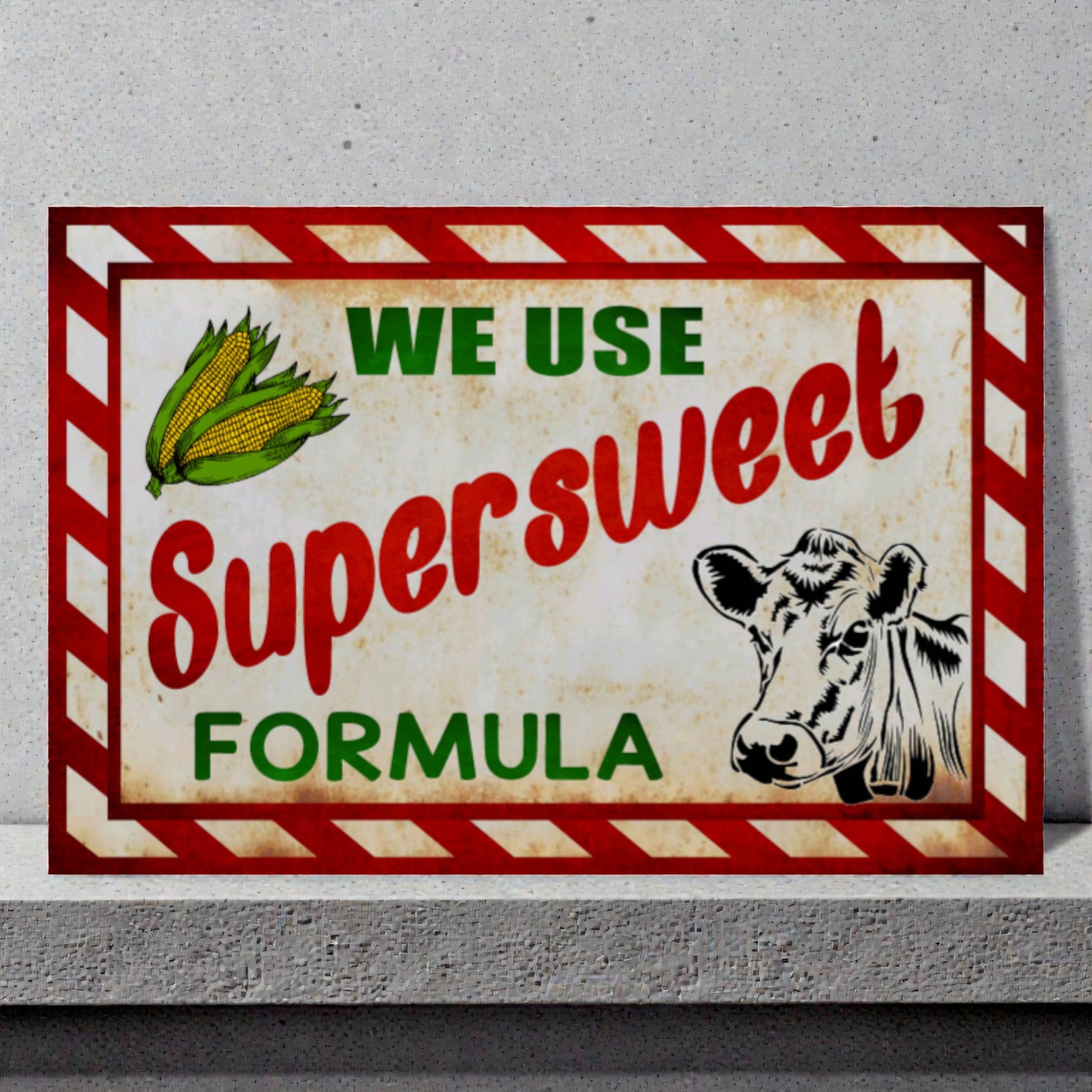 Vintage-style sign with a cow and corn, promoting 'Supersweet Formula' on a gray background.