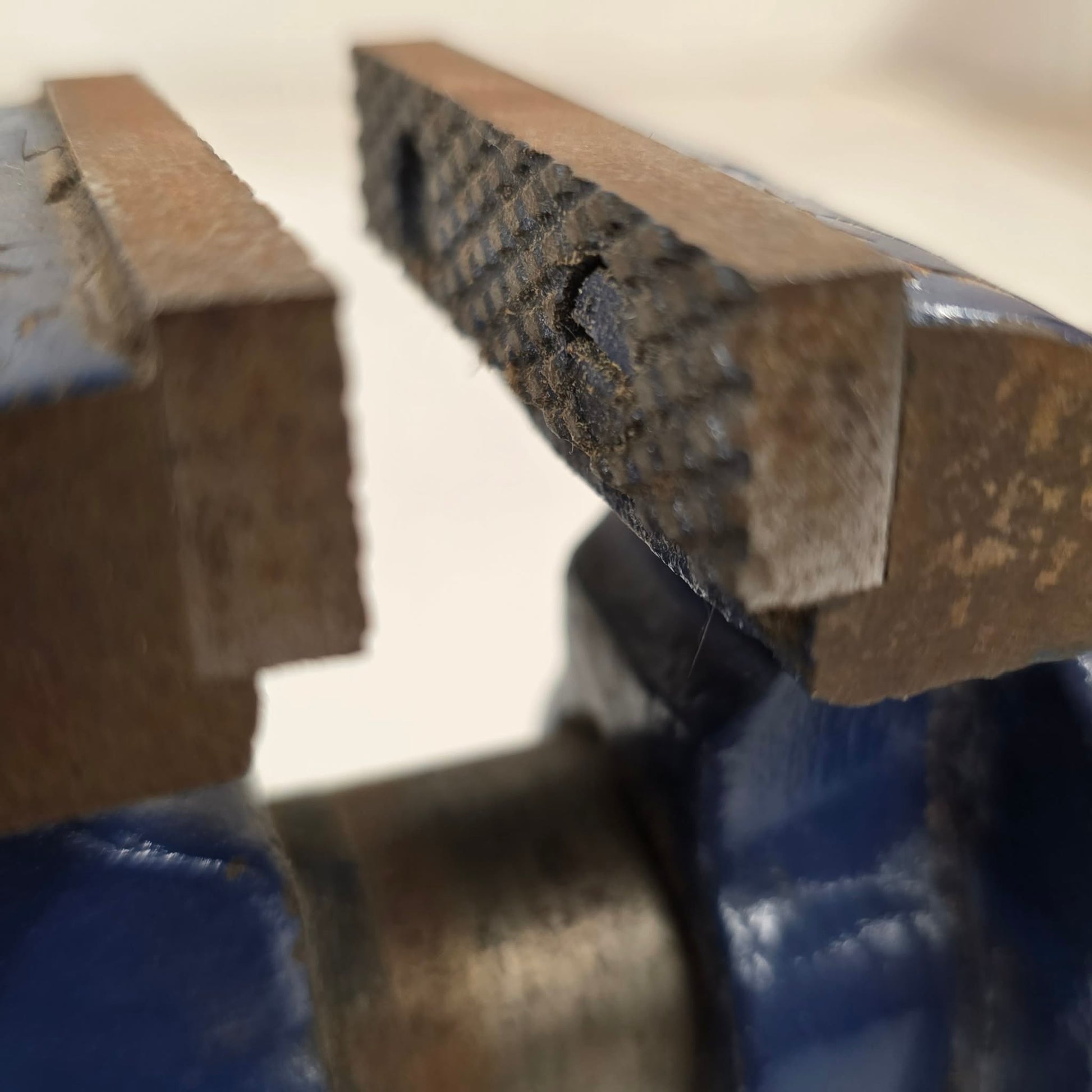 Close-up of a metal vise holding a piece of wood.