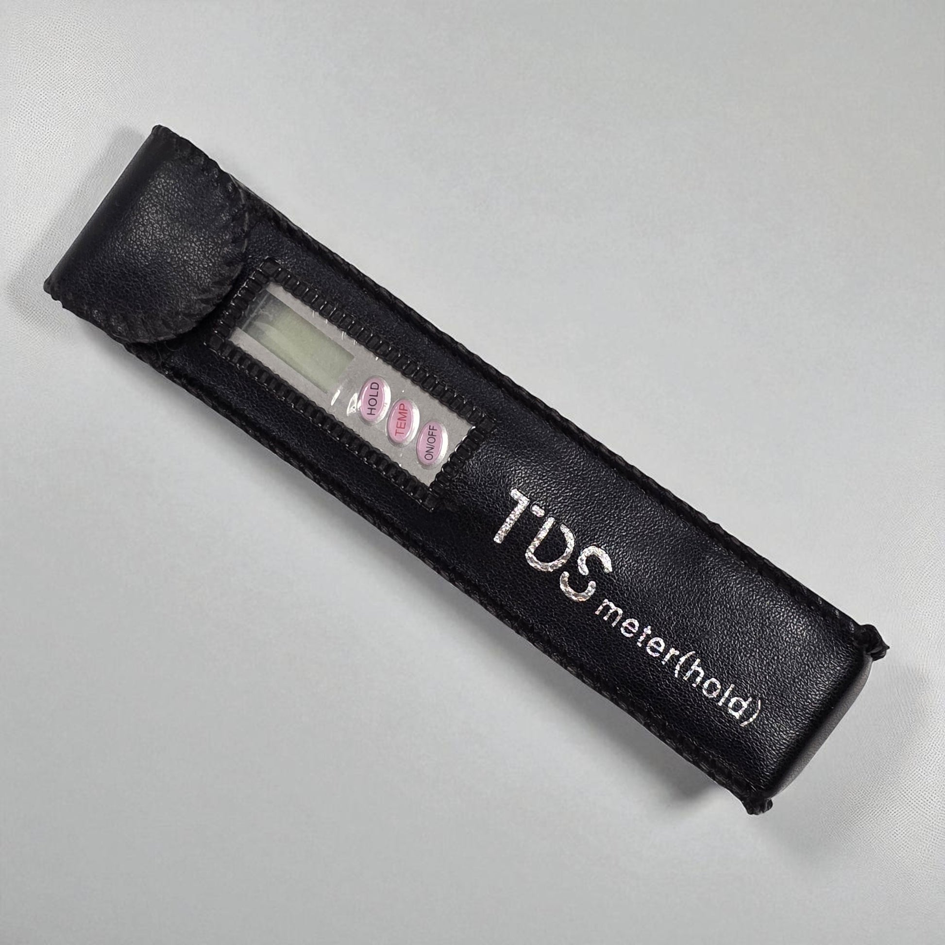 Black TDS meter with digital display on a gray background