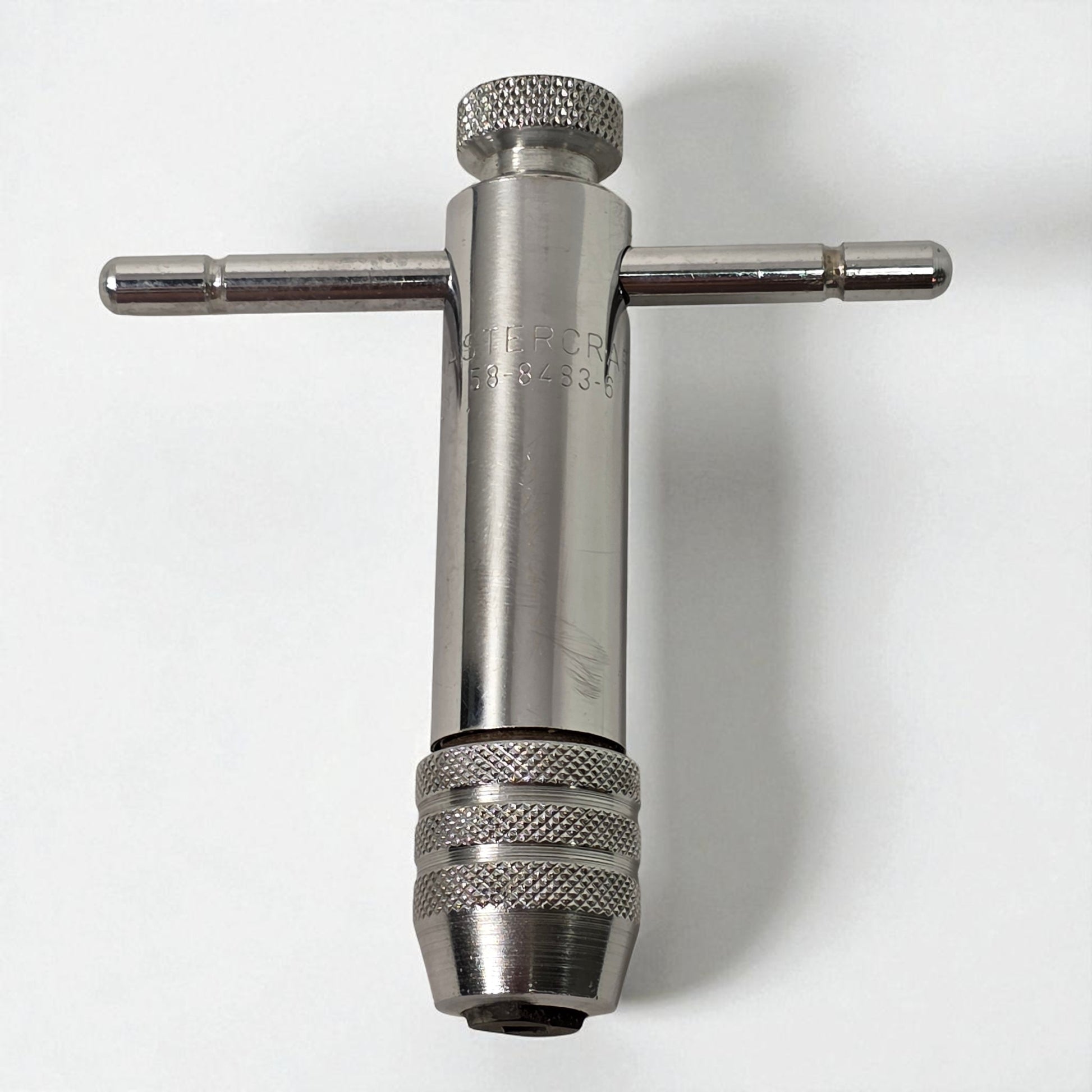 Metal t-handle drill bit on a white background