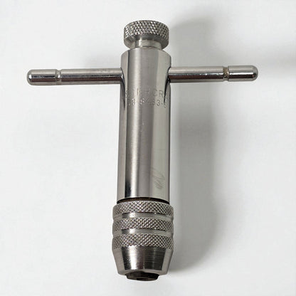 Metal t-handle drill bit on a white background