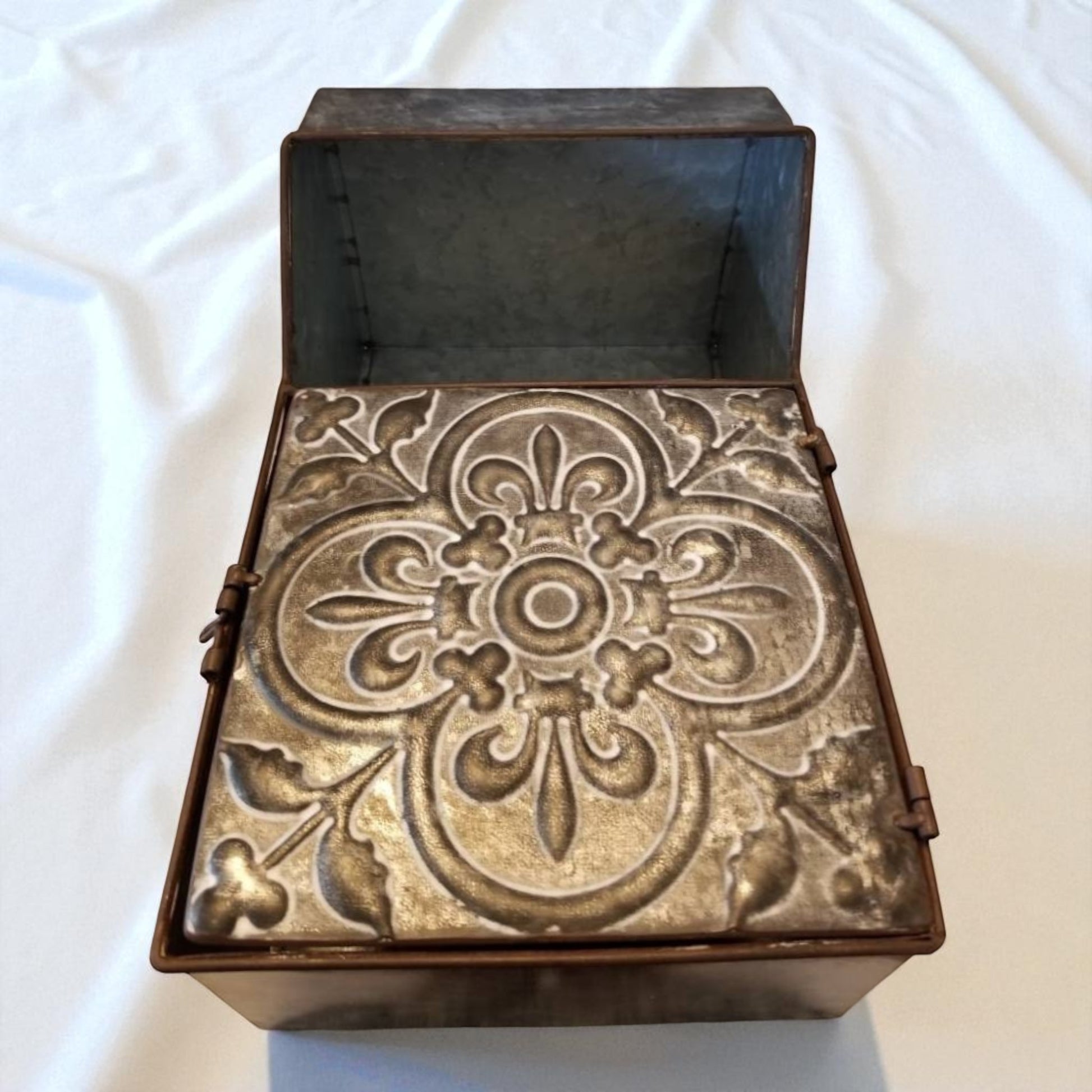 Decorative metal box with intricate patterns on a white background