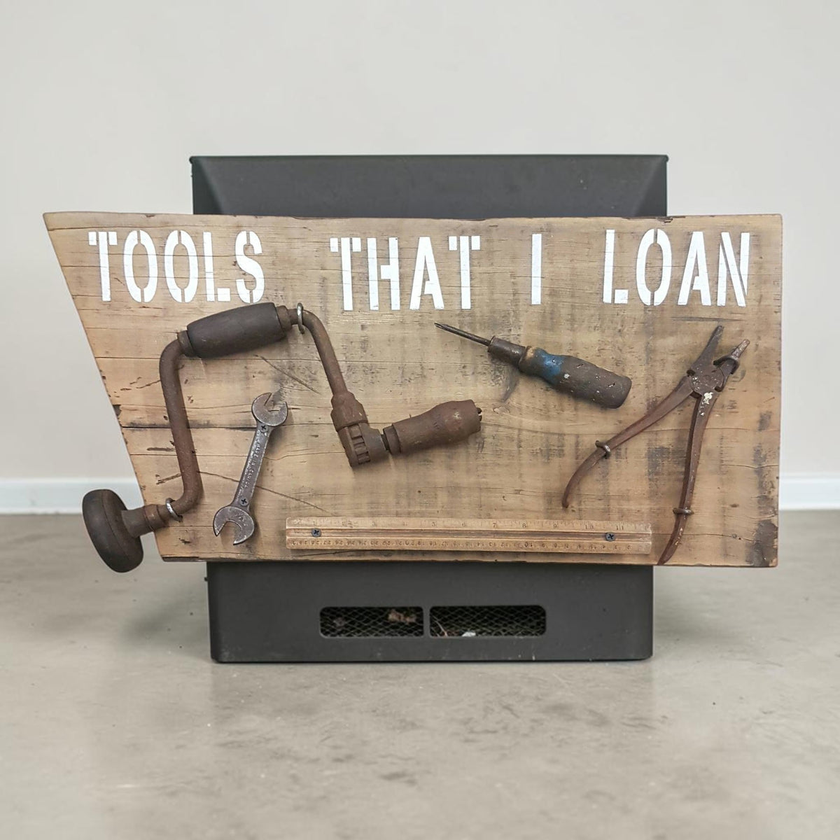 Handmade rustic Tools That I Loan garage sign with five useless tools
