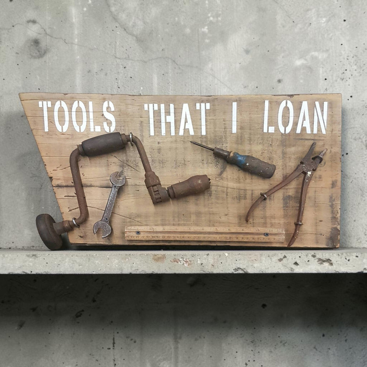 Handmade rustic Tools That I Loan garage sign with five useless tools
