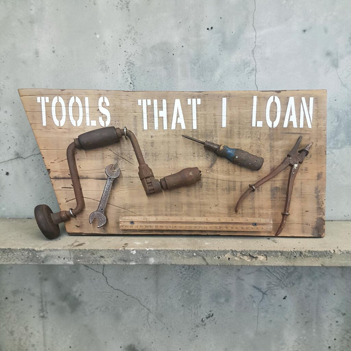 Handmade rustic Tools That I Loan garage sign with five useless tools
