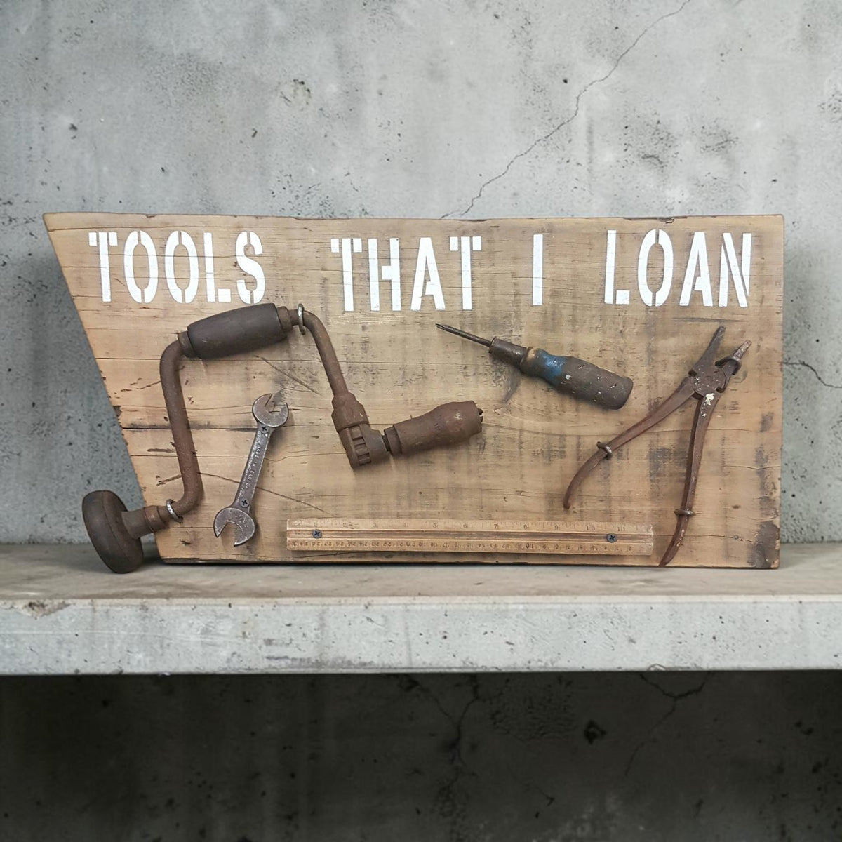 Handmade rustic Tools That I Loan garage sign with five useless tools
