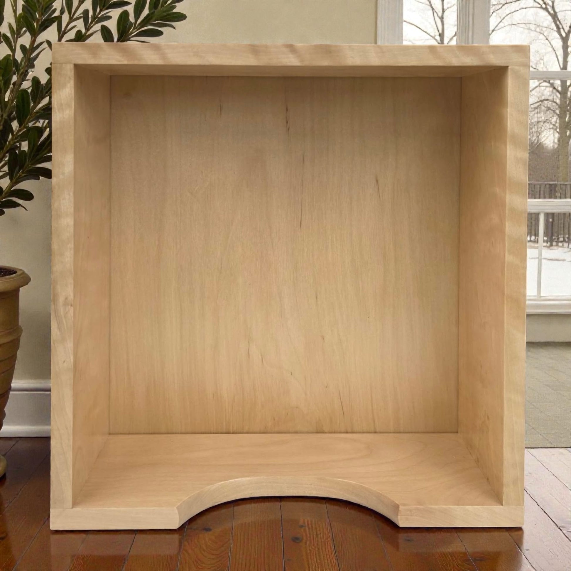 Wooden bookshelf against a neutral wall with a plant and window in the background