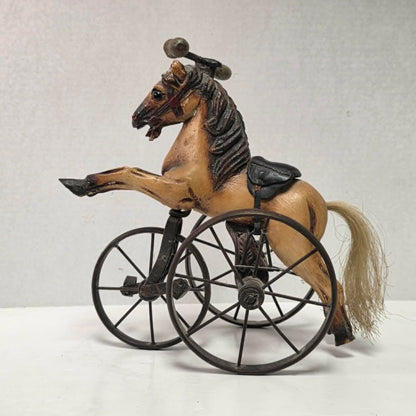 Vintage miniature wooden toy horse ride-on velocipede with carved wooden body, iron wheels, and pedals. Antique collectible toy display piece from a bygone era.
