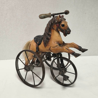 Vintage miniature wooden toy horse ride-on velocipede with carved wooden body, iron wheels, and pedals. Antique collectible toy display piece from a bygone era.