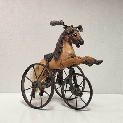 Vintage miniature wooden toy horse ride-on velocipede with carved wooden body, iron wheels, and pedals. Antique collectible toy display piece from a bygone era.