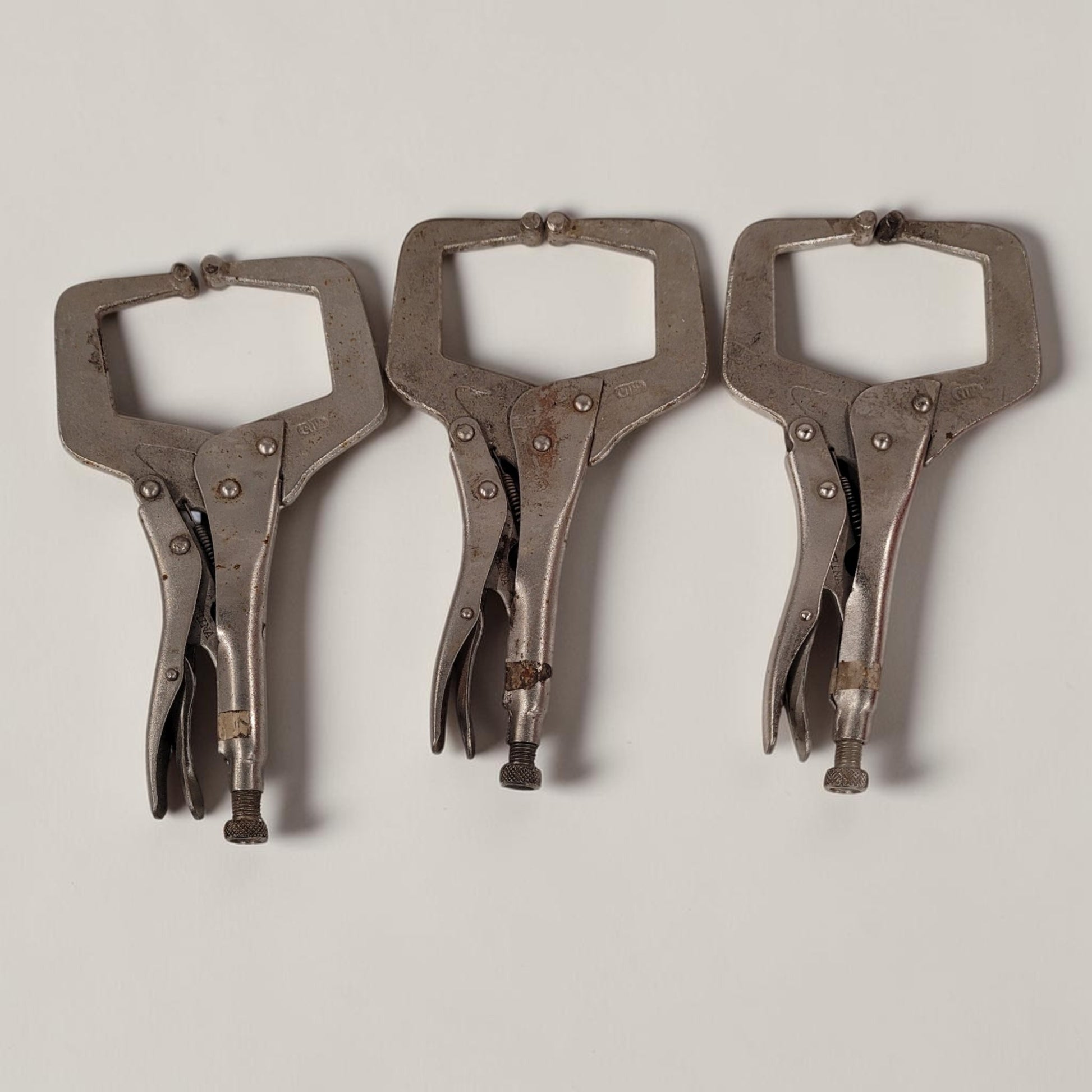 Set of three 11 inch C-clamp locking pliers used for welding and metal fabrication in a workshop setting.