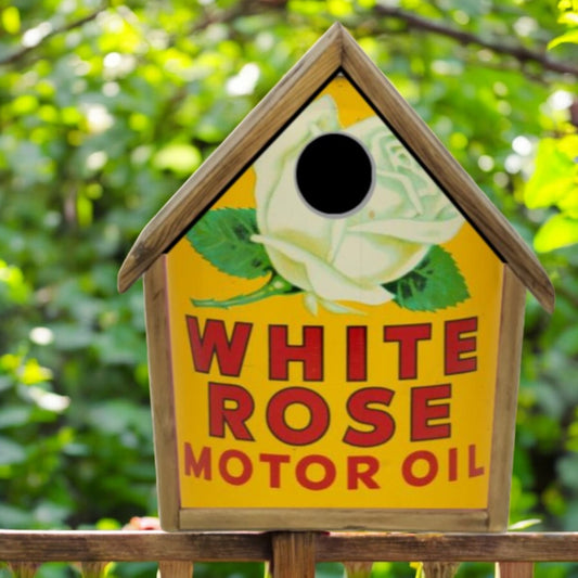 Birdhouse with White Rose Motor Oil branding against a green leafy background