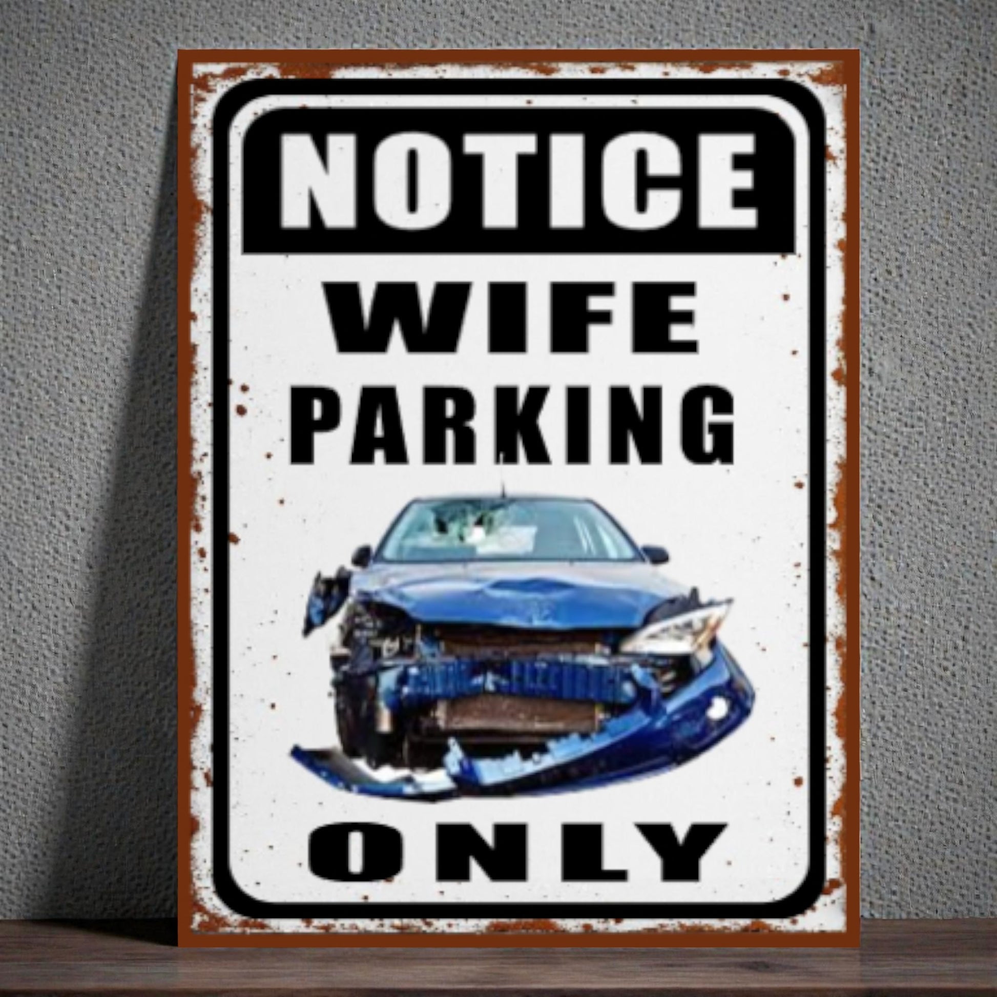 Metal sign with a car and text 'Notice Wife Parking Only' on a gray wall.