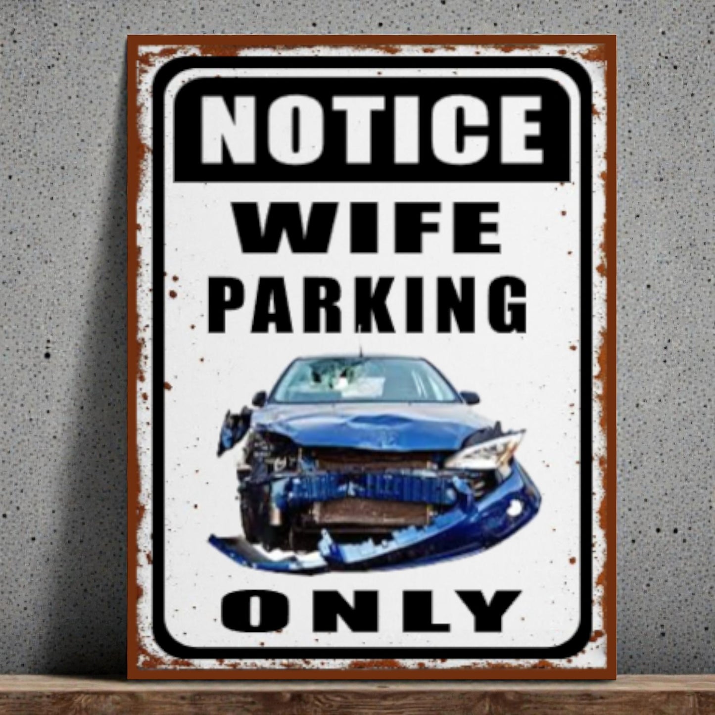 Metal sign with a car illustration and text 'Notice Wife Parking Only' on a gray background.