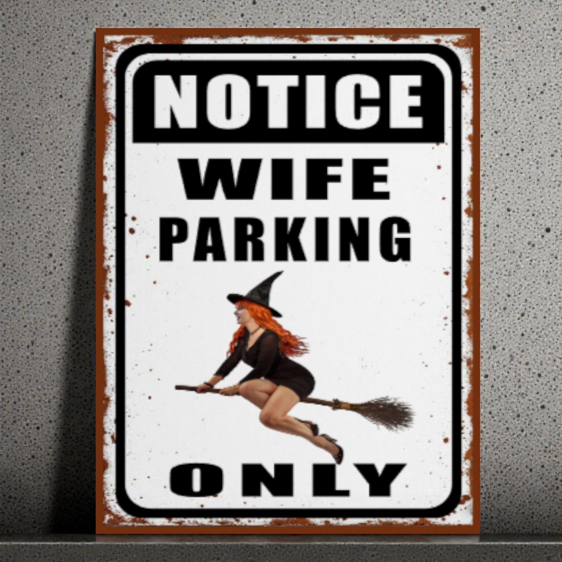Metal sign with a witch design and text 'Notice Wife Parking Only' on a textured wall background.