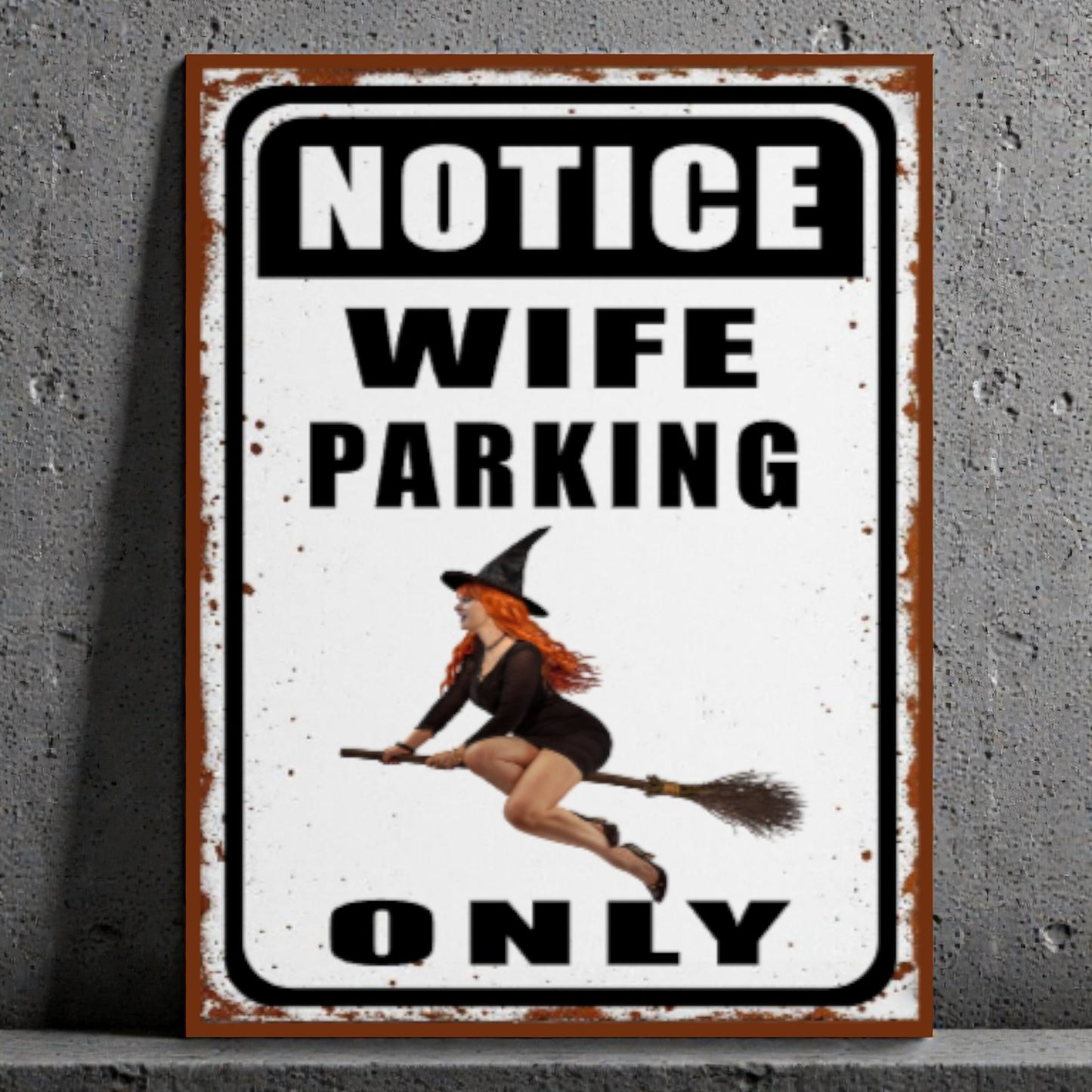 Metal sign with a witch design and text 'Notice Wife Parking Only' on a gray background